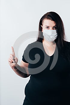 Woman in medical mask and gloves pointing up