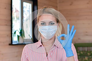 Woman in medical mask and gloves shows thumbs up. medical person shows like. photo