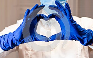 Woman with a medical mask and hands in latex glove shows the symbol of the heart. Doctor for the heart. Love to our pancreas. Love