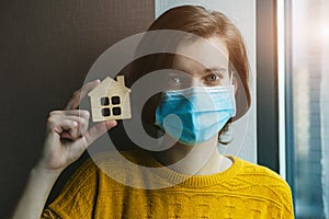 Woman in medical mask holding model go house.