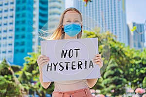 Woman in medical mask prevents coronavirus disease holds a poster not histeria Hand written text - lettering isolated on photo