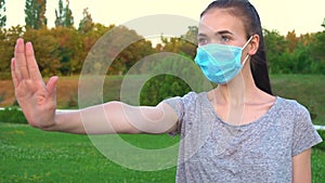 Woman in medical mask is show stop gesture by hand.