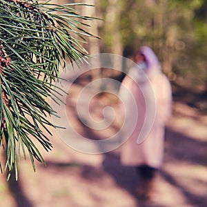 A woman in a medical mask walks along a path in a summer forest, selective focus. Concept of recovery from the flu virus pandemic