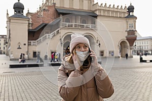 A woman in a medical protective mask talks on a cell phone