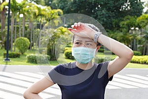 The woman in medical protective mask, she tired from a workout rest. female athlete suffering a headache and dizziness