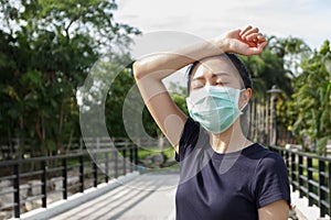 The woman in medical protective mask, she tired from a workout rest. female athlete suffering a headache and dizziness