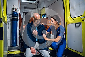 Woman in medical uniform talks friendly and smiles to a man in blanket