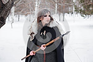 The woman is a medieval warrior of the Viking Age in the winter in the forest.