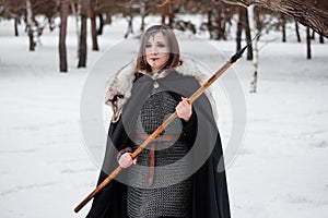 The woman is a medieval warrior of the Viking Age in the winter in the forest.