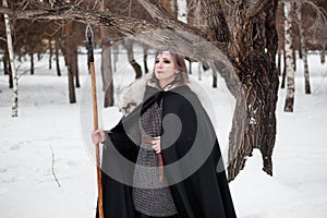 The woman is a medieval warrior of the Viking Age in the winter in the forest.