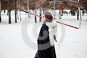 The woman is a medieval warrior of the Viking Age in the winter in the forest.