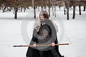 The woman is a medieval warrior of the Viking Age in the winter in the forest.