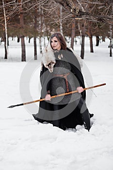 The woman is a medieval warrior of the Viking Age in the winter in the forest.