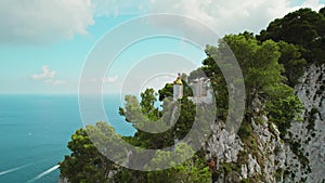 Woman meditates in lotus position on Vibrant Clifftop Oasis Overlooking the Sea. Sunlight splashes over the Capri