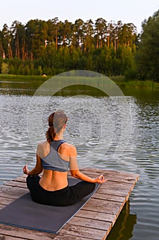 A woman meditates in nature by the lake. The concept of realizing the meaning of life photo