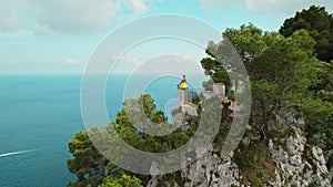 Woman meditates over the sea on rocky cliff. Breathtaking aerial view of Capri Island overlooking the sea.