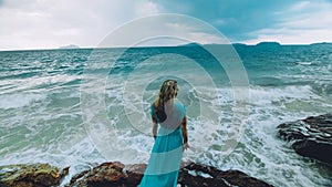 Woman meditates, relaxes on a rock reef hill in stormy morning rain cloudy sea. Concept feminine, relax, sexual health