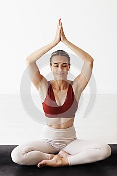 A woman meditates in a yoga studio. She is in Siddhasana and anjali mudra hands photo