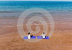 Woman meditating on the beach aerial