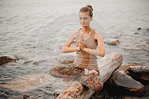 Woman meditating at the beach . yoga retreat. namaste in lotus pose