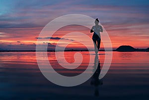 Woman meditating in calm yoga pose on sunset sea beach