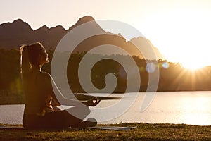 Woman Meditating Doing Yoga By Lake And Mountains At Sunset 