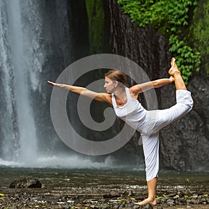 Woman meditating doing yoga between waterfalls