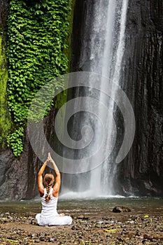 Woman meditating doing yoga between waterfalls