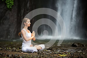 Woman meditating doing yoga between waterfalls