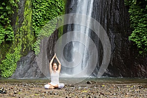 Woman meditating doing yoga between waterfalls