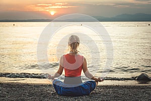 Woman meditating at the Garda Lake. Sunset.