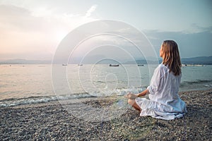 Woman meditating at the Garda Lake. Sunset.