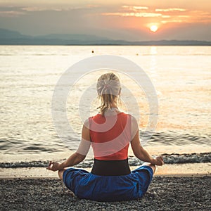 Woman meditating at the Garda Lake. Sunset.