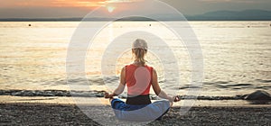 Woman meditating at the Garda Lake. Sunset.