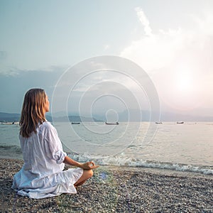 Woman meditating at the Garda Lake. Sunset.