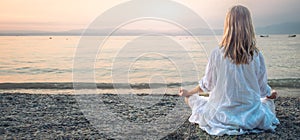 Woman meditating at the Garda Lake. Sunset.