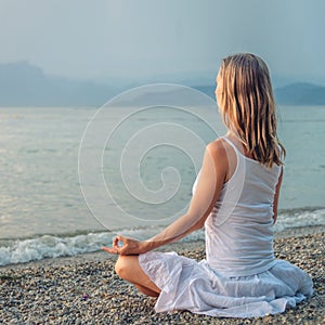 Woman meditating at the Garda Lake. Sunset.