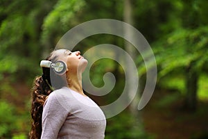 Woman meditating listening audio guide in a forest