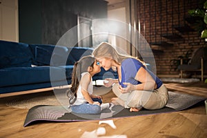 Woman meditating at living room with her daughter while bonding to each other