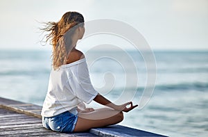 Woman meditating in Lotus Pose on pier