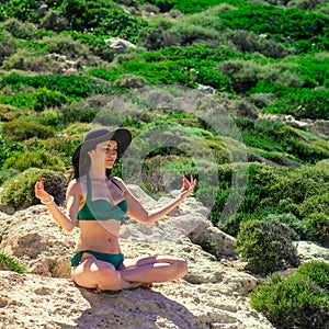 Woman meditating in Lotus pose on the rocks. the concept of rest, relaxation, spiritual peace, yoga.