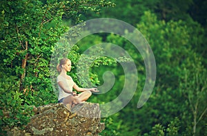 woman meditating in lotus posture, doing yoga on top of the mountain