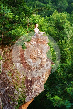 woman meditating in lotus posture, doing yoga on top of the mountain