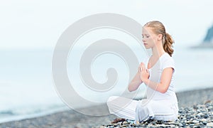 Woman meditating in lotus yoga on beach