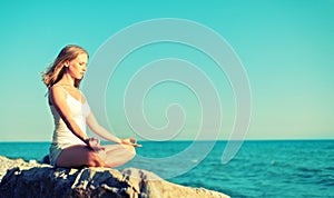 Woman meditating in lotus yoga on beach photo
