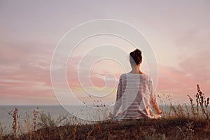 Woman meditating near sea, back view. Space for text