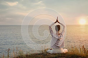 Woman meditating near sea, back view. Space for text