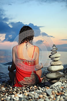 Woman meditating near to pyramid from pebble