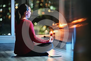 Woman Meditating At Night With Smartphone App For Yoga