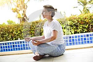 Woman meditating at pool side